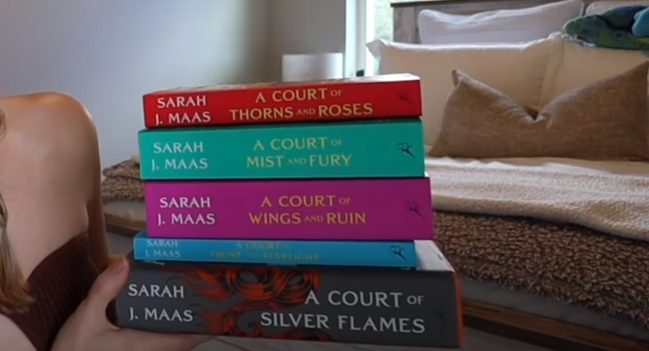 Female holding a complete collection of A Court of Thorns and Roses books