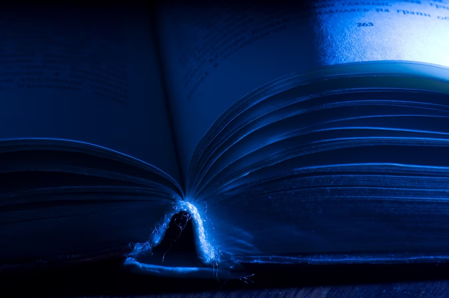 Close-up of open book pages in a dimly lit room with a soft blue light